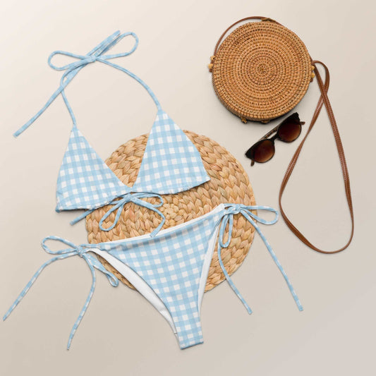 Blue Gingham Check String Bikini Set with adjustable ties and UPF 50+ protection displayed next to round woven bag and brown sunglasses.